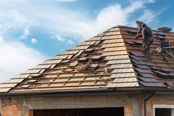 roof maintenance process of building, roofer workers installing grey metal tile on top of roof with wooden frame outdoors on blue sky background